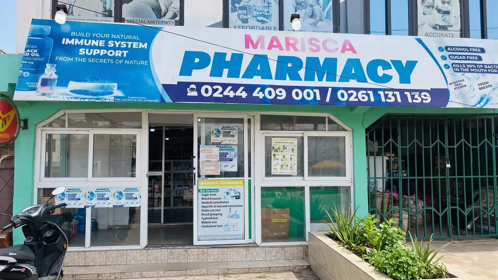 The Kumasi branch of Marisca Pharmacy, with the services board displayed on the door.